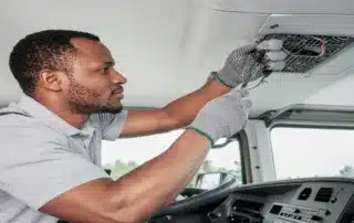 Technician servicing the interior ceiling panel inside a truck cab