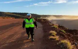 Worker in safety vest walking on an open-pit mine access road