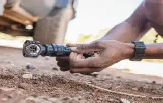 Technician connecting an electrical cable assembly on outdoor terrain