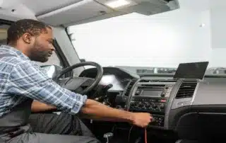 Mechanic inspecting dashboard electronics inside a vehicle cabin