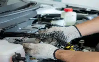 Close-up of a mechanic in protective gloves repairing engine bay wiring